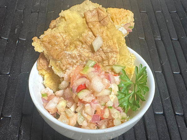 Bowl of ceviche with tortilla chips on a black textured surface